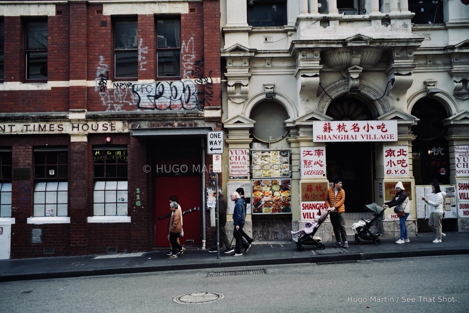 Pedestrians passing ornate façades and a Chinese restaurant
